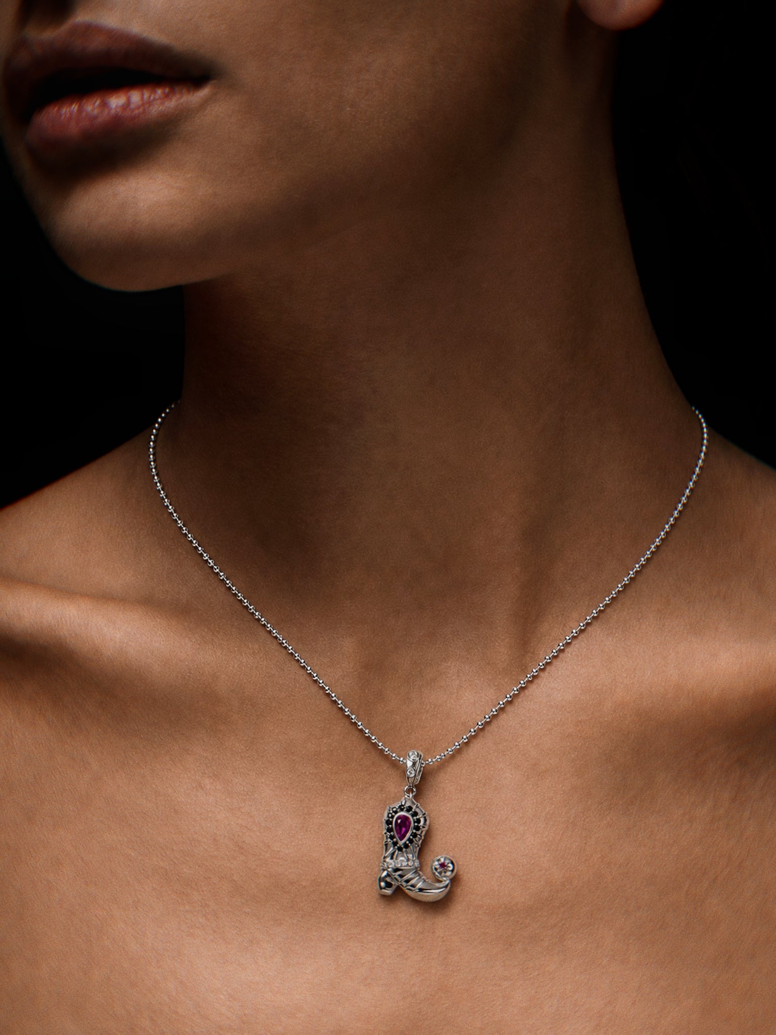 PurpleSea Emperor Iron Boot Pendant, sterling silver boot-shaped pendant with vivid pink stones and sculptural armor-inspired detailing, shown worn as a necklace on a model